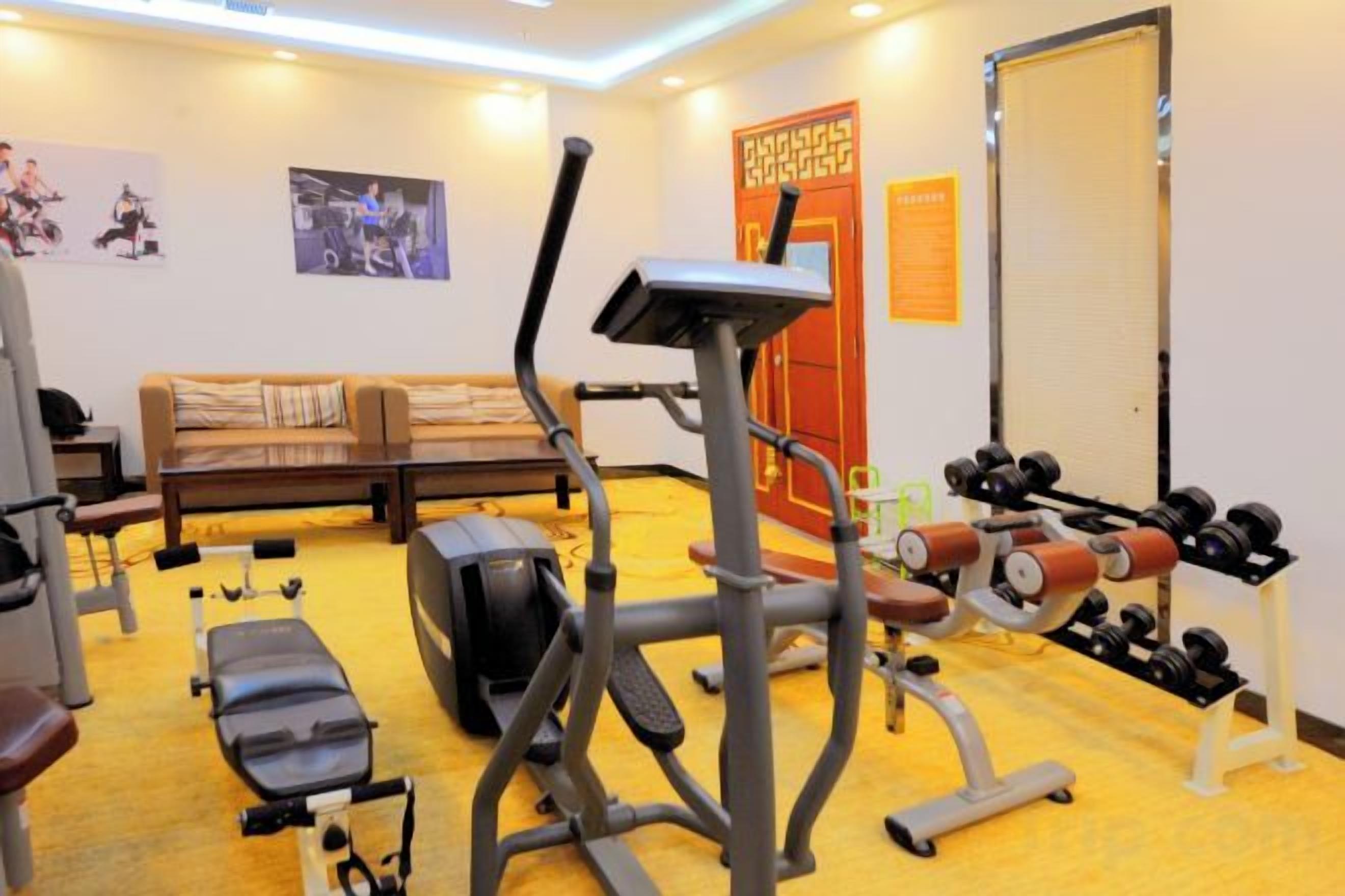 Un gimnasio con equipo de ejercicio, un sofá y una puerta.