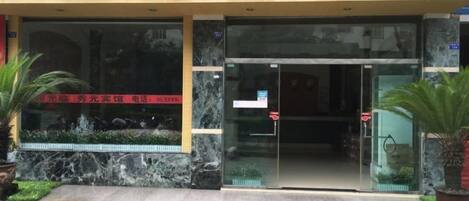 L’entrée d’un hôtel, avec une porte en verre et une enseigne au-dessus.