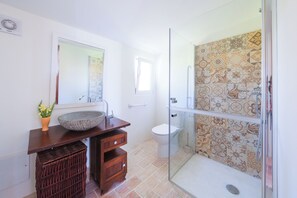A bathroom with a large bowl sink, a mirror above it, a toilet, and a shower with patterned tiles. - Monte das Estrelas (Tavira)