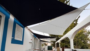 A covered outdoor area with a paved floor, white chairs, and tables. - Monte das Estrelas (Tavira)