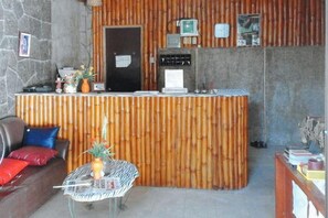 Un área de recepción con un mostrador de madera, una puerta negra y una pared de piedra.