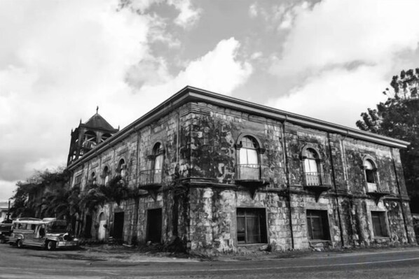 Un edificio antiguo y abandonado con un campanario, ventanas arqueadas y una fachada desgastada.