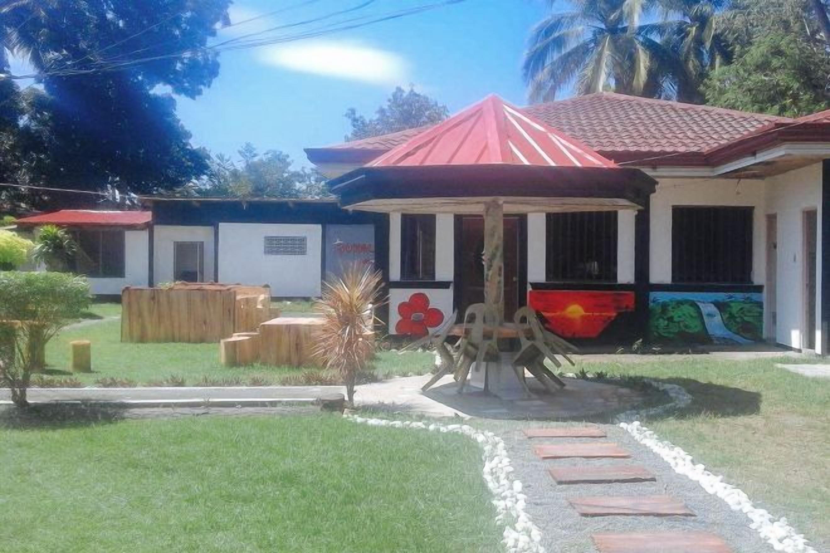 Un edificio con techo rojo, una zona de estar techada al aire libre y un mural en la pared.