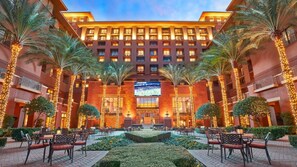 Un hotel con un cortile centrale, palme e aree salotto all'aperto.