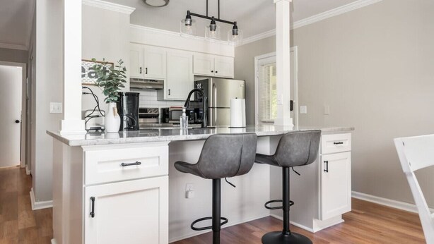 Een moderne keuken met witte kasten, een centraal eiland met barstoelen en roestvrijstalen apparatuur.