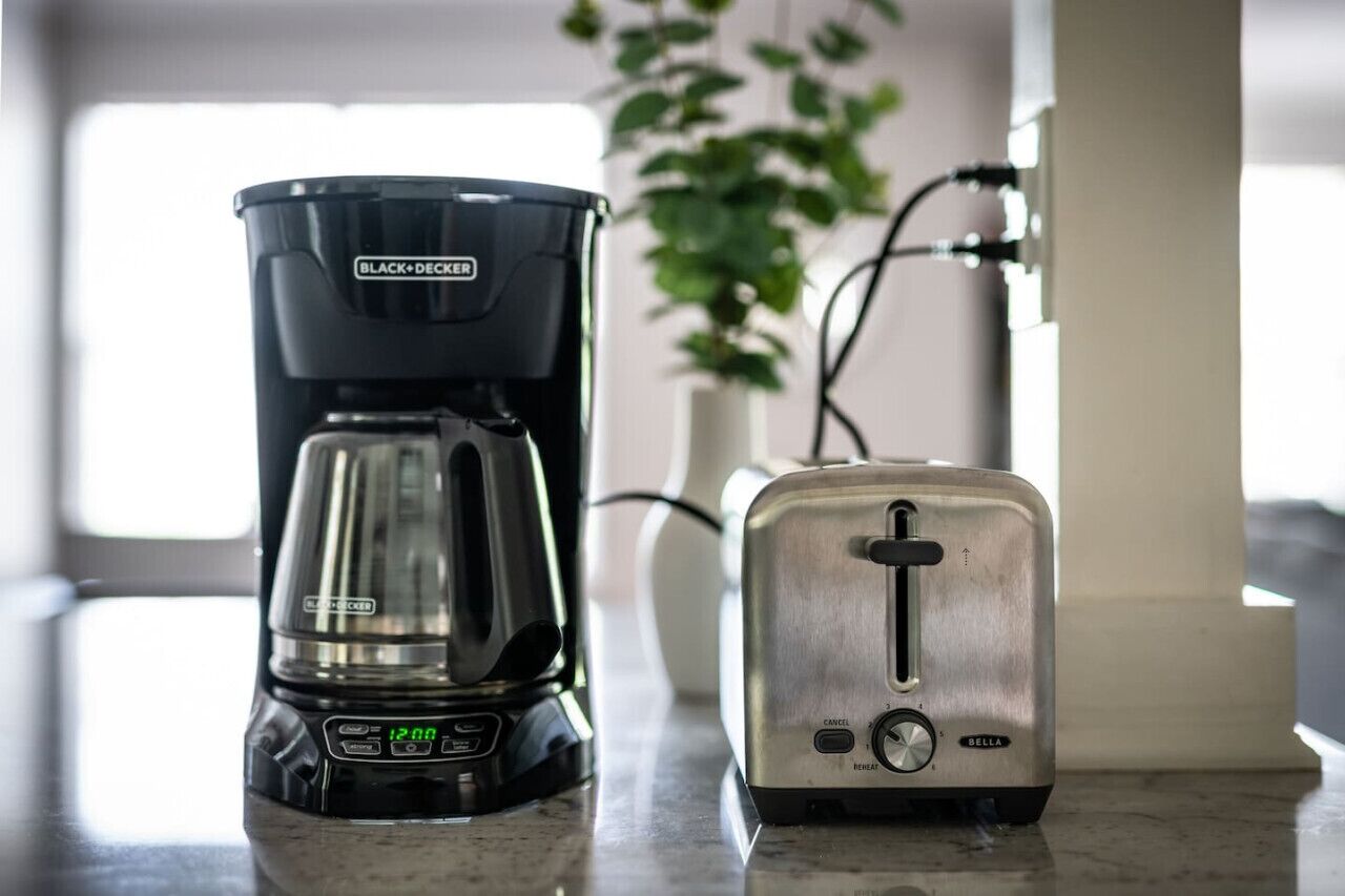A kitchen counter with a BLACK+DECKER coffee maker and a DELL toaster.