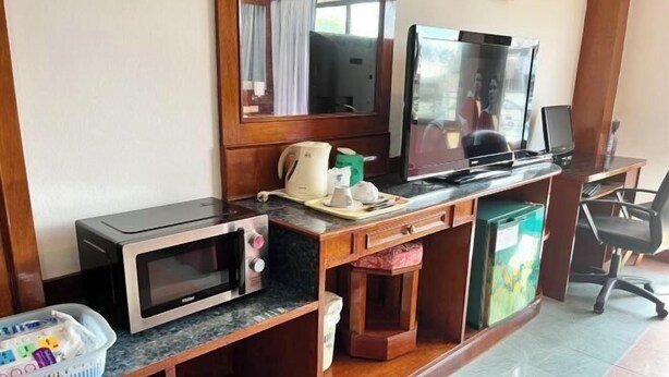 A compact hotel room with a kitchenette, a television, a desk with a computer, and a chair. - Lamai Hotel (Phuket)