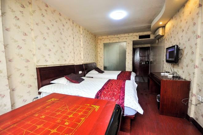A hotel room with two beds, a television, and a desk.