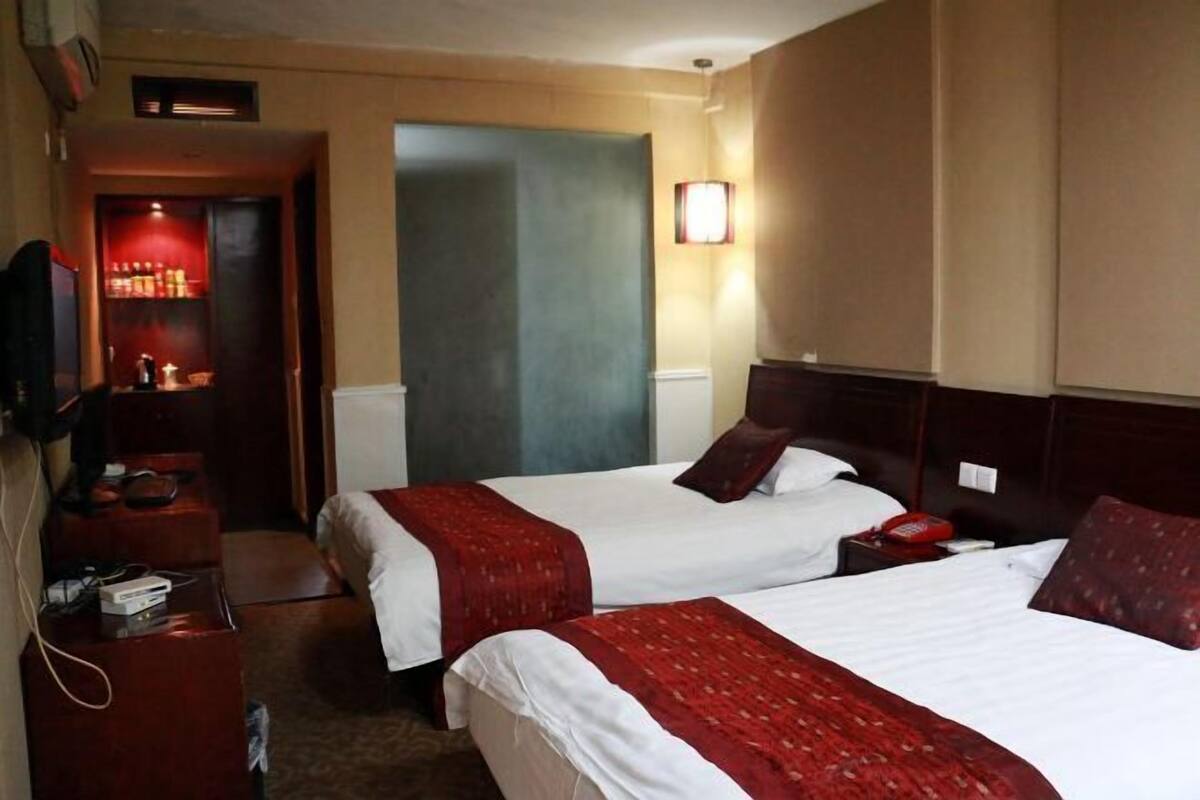 Ein Hotelzimmer mit zwei Betten, einem Fernseher, einem Schreibtisch und einer Minibar.