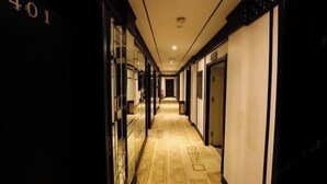 Un pasillo de hotel con alfombra estampada, puertas a ambos lados y un cartel con el número 401 a la izquierda.