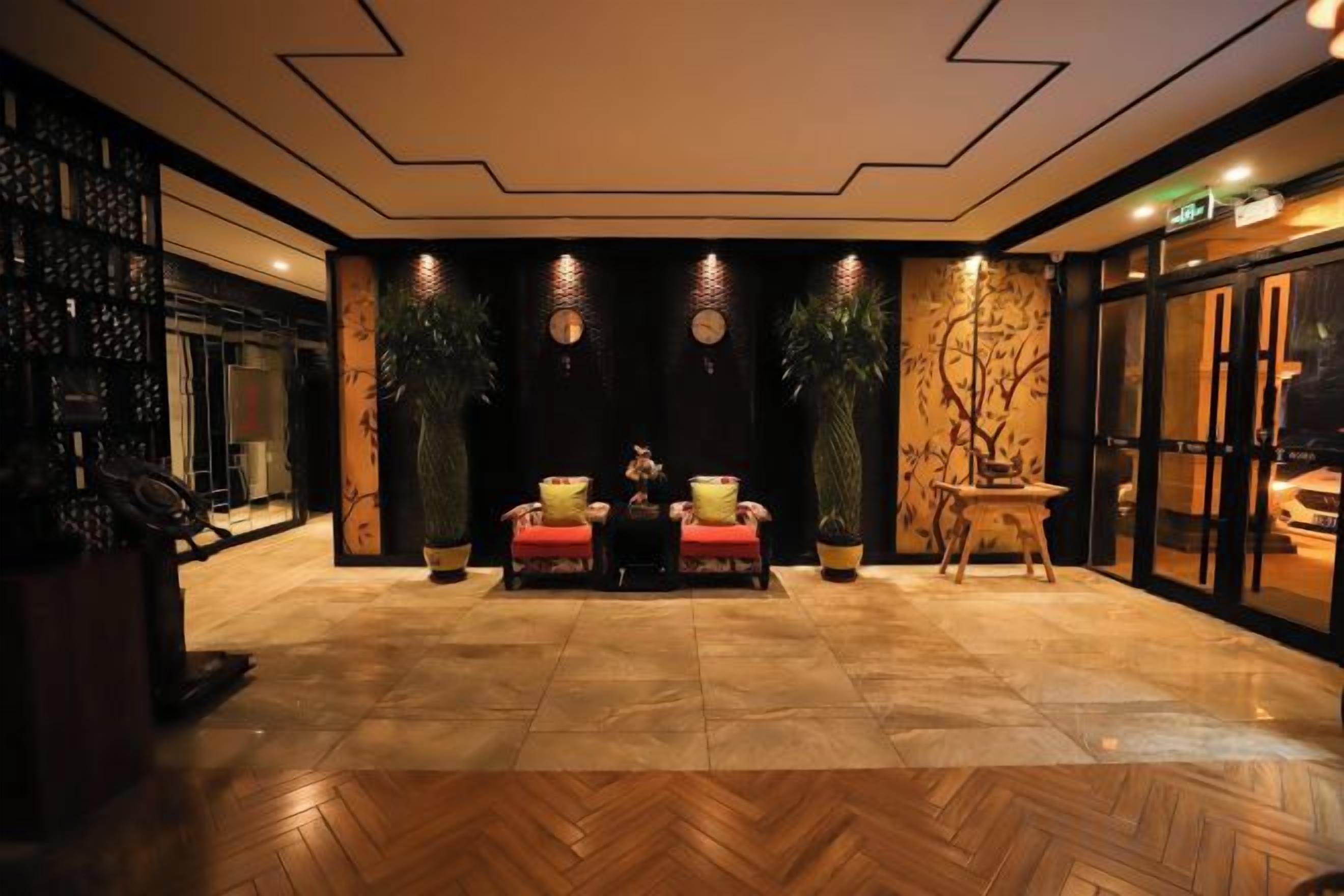 Un hall con suelo de espiga, dos sofás, una mesita y una pared decorativa con plantas.