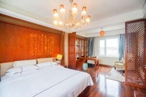 Un dormitorio con una cama grande, una araña, una estantería y vistas a través de una ventana.