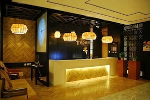 Un espace d’accueil doté d’un parquet en bois disposé en chevrons, d’un comptoir de réception et de trois lampes suspendues.