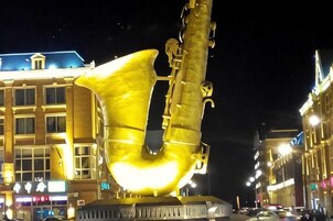 Una gran escultura iluminada de un saxofón en un entorno urbano.