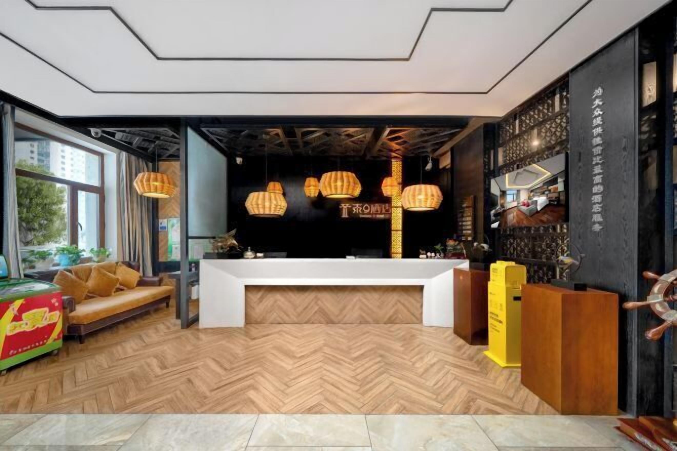 Una moderna zona de recepción con suelo de madera en espiga, un mostrador blanco y una pared negra con detalles decorativos.