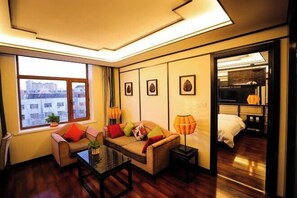 A modern hotel room with a sofa, a coffee table, a lamp, and a bed.