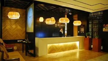 A reception area with a wooden reception desk, pendant lighting, and a decorative wall.