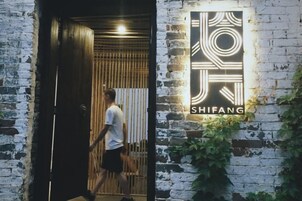 Una persona sale de un edificio con un cartel que dice 'SHIFANG' en la pared.