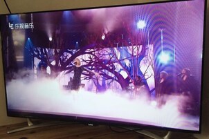 Un televisor muestra una escena con una persona vestida de oscuro, una estructura similar a un árbol y un fondo brumoso.