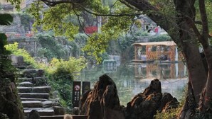 A serene outdoor area with a pond, stone steps, and a wooden structure. - Shifang Chuanshe Boutique Inn (Zhaoping)