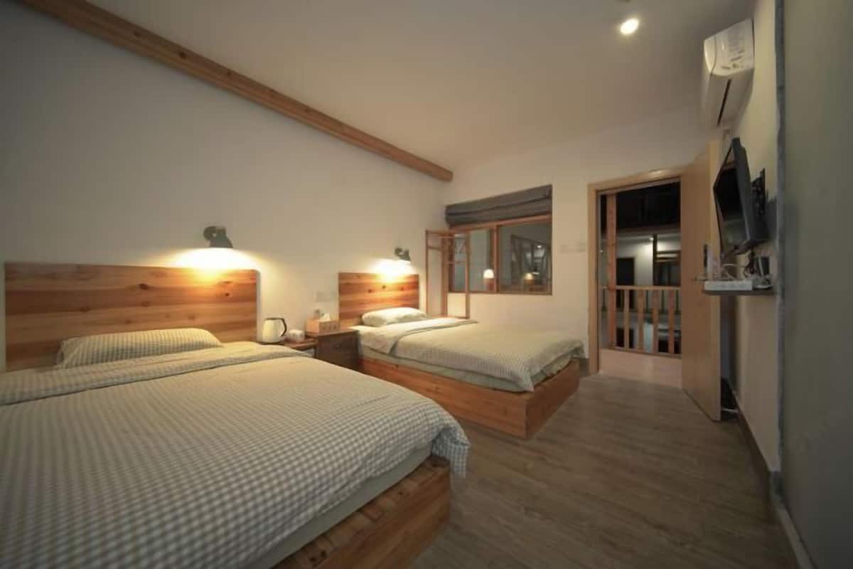 Un dormitorio con dos camas, cabeceros de madera, mesitas de noche, un televisor y una ventana.