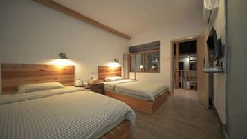 A bedroom with two beds, wooden headboards, bedside tables, a TV, and a window.