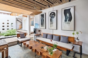 Un espacio habitable de concepto abierto con techo de madera, un sofá, una mesa de comedor y un banco. Hay obras de arte enmarcadas en la pared y una planta en maceta sobre el banco.