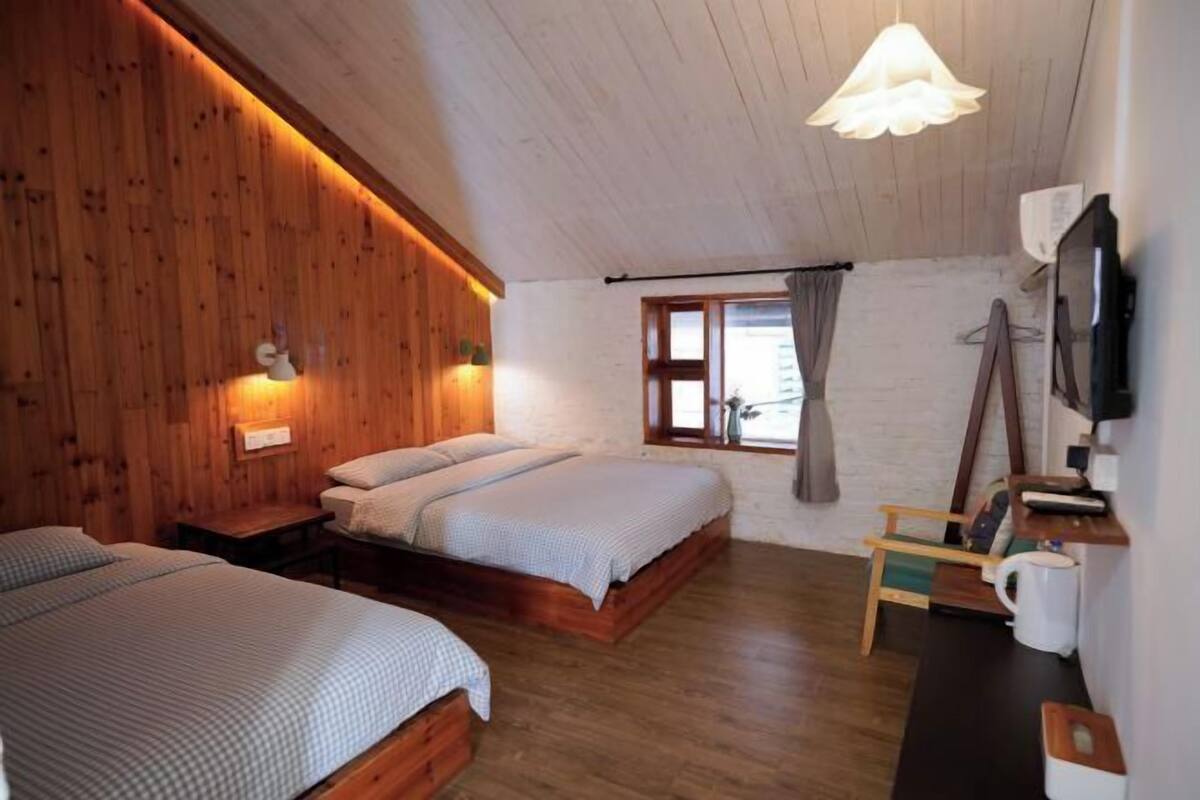 Un dormitorio acogedor con paredes de madera, una cama, un escritorio y una televisión.