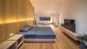 A modern bedroom with a large bed, wooden paneling on one wall, a TV, and a window with a view. - Shifang Chuanshe Boutique Inn (Zhaoping)