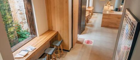 Un interior moderno con un banco y taburetes de madera, una zona de cocina y vistas a través de una ventana.
