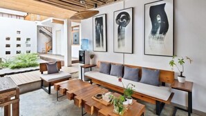 A modern living room with a wooden bench, a sofa, and a coffee table. There are three abstract paintings on the wall. - Shifang Chuanshe Boutique Inn (Zhaoping)