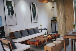 A modern living room with a sofa, coffee table, and chairs. There are framed artworks on the wall and a small table with decorative items. - Shifang Chuanshe Boutique Inn (Zhaoping)