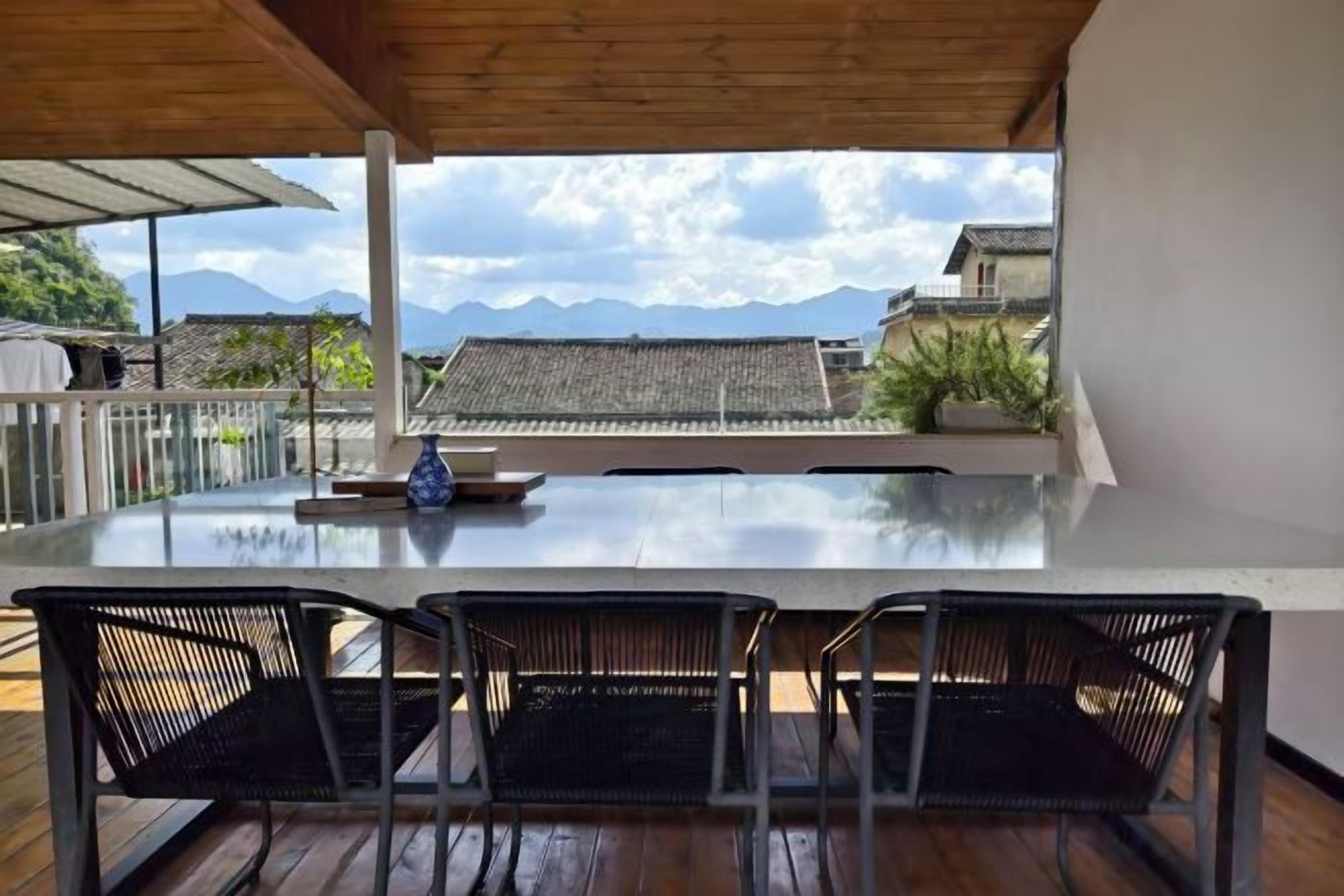Un espacio de comedor al aire libre con mesa y sillas, con vistas a un paisaje montañoso.