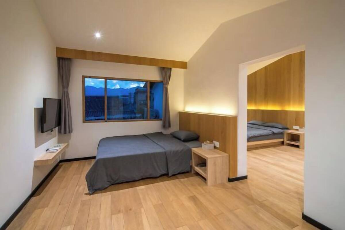 Una habitación de hotel moderna con una cama grande, televisión, mesita de noche y ventana con vistas a la ciudad.