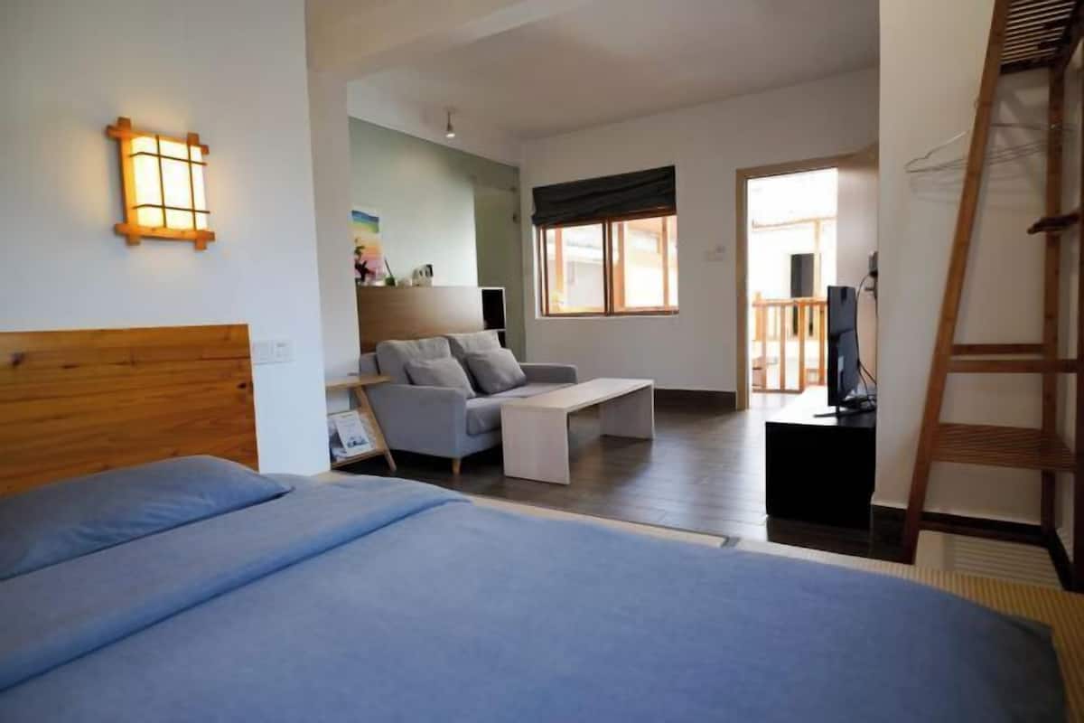 Un dormitorio con cama, sofá, televisor y ventana.