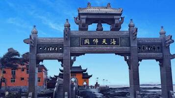 Un arco chino tradicional con inscripciones que conduce a un edificio con techo de tejas.