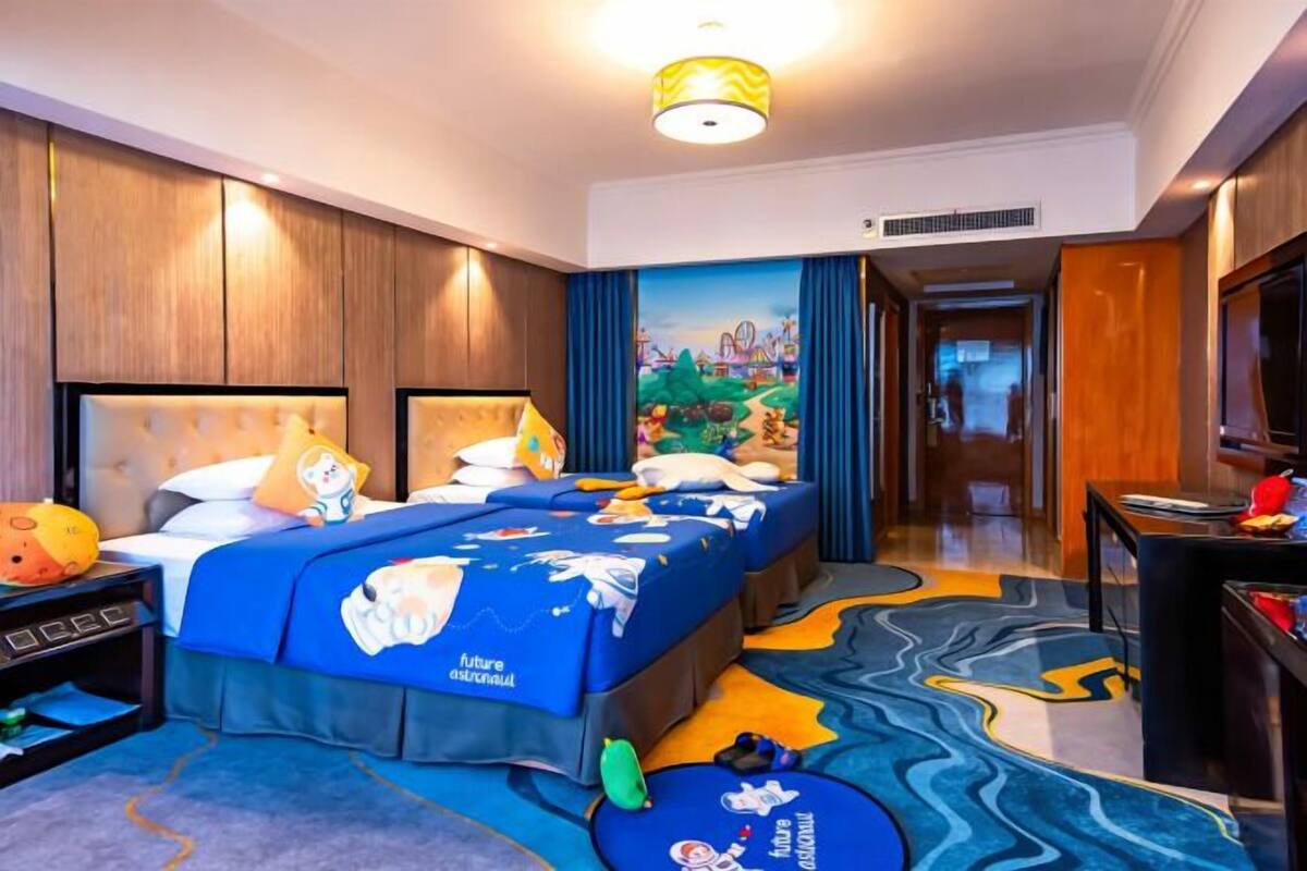 A hotel room with a large bed, a desk, and a mural on the wall.