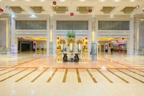 A spacious lobby with a polished floor, a reception desk, and a large plant centerpiece. - Shishi Wanjia International Hotel (Shishi)