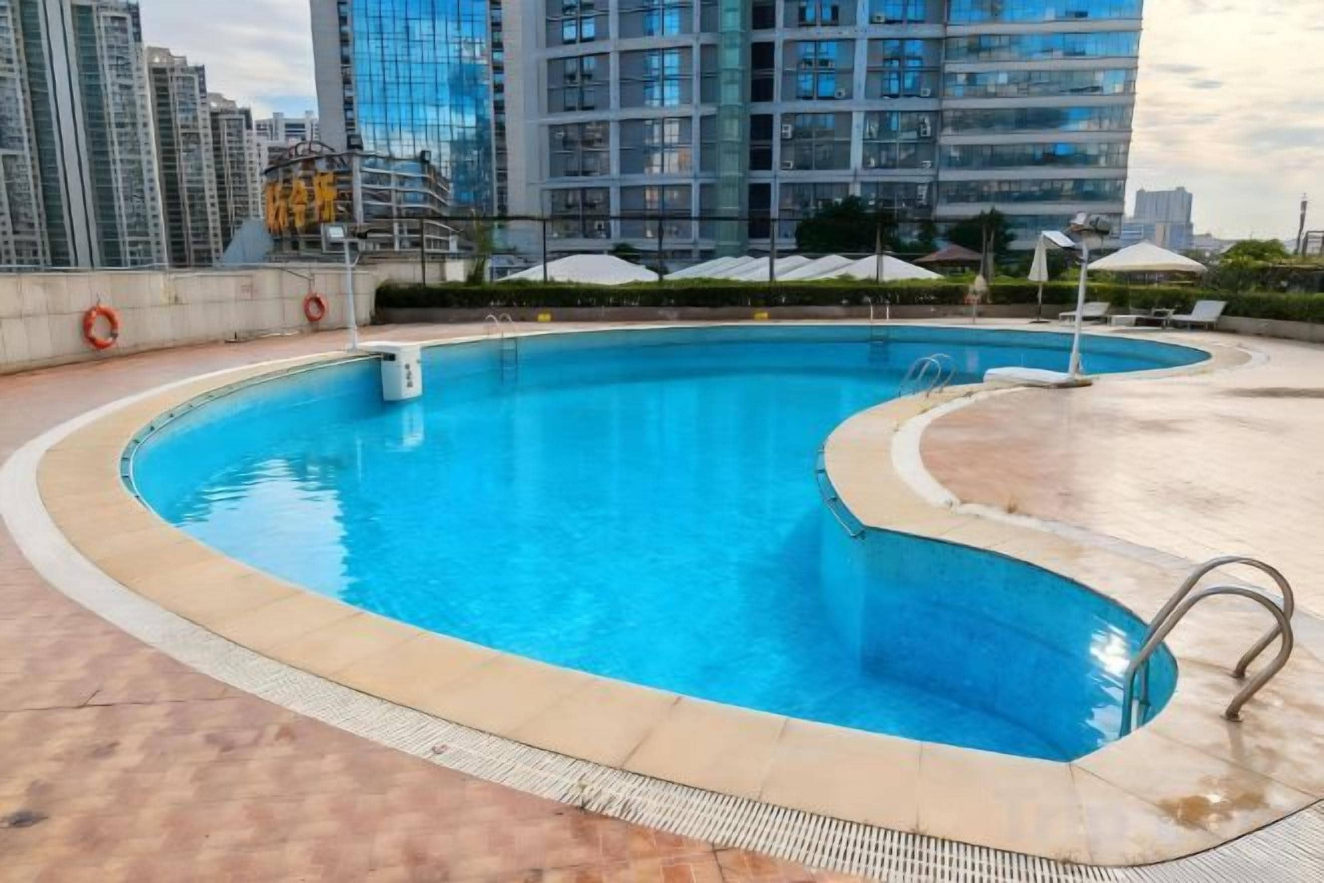 A swimming pool with a curved edge, surrounded by a tiled deck.