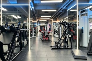Une salle de sport équipée de divers appareils d’exercice, de miroirs et dotée d’un intérieur propre et bien éclairé.