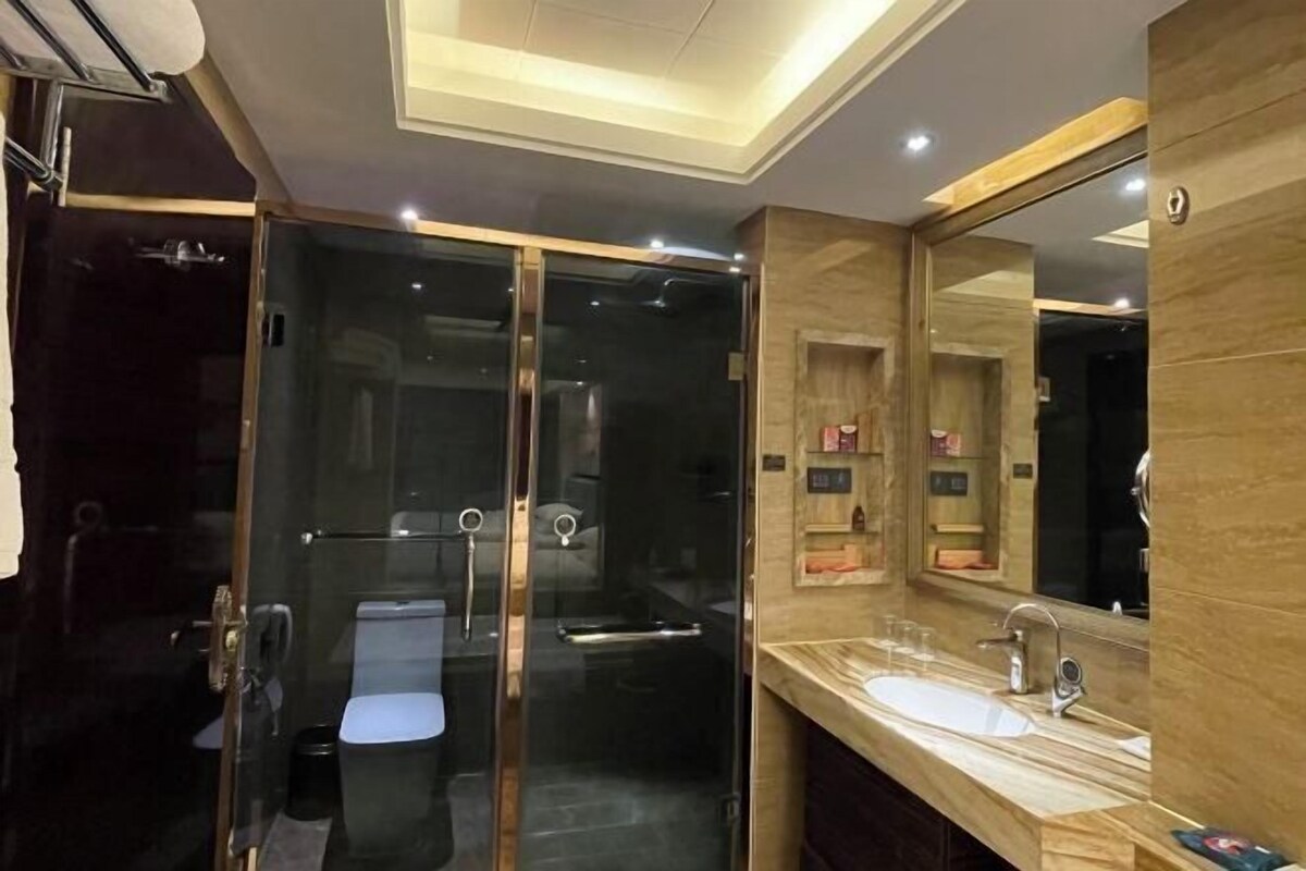 A modern bathroom with a glass-enclosed shower, a large mirror, and a marble countertop.