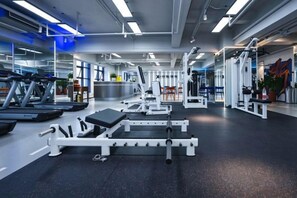 Ein Fitnessraum mit Trainingsgeräten, Laufband und Langhantelbank.