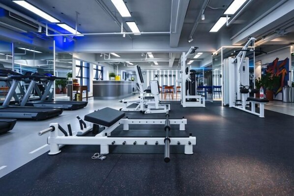 Une salle de sport équipée de matériel d’exercice, d’un tapis de course et d’un banc de musculation.