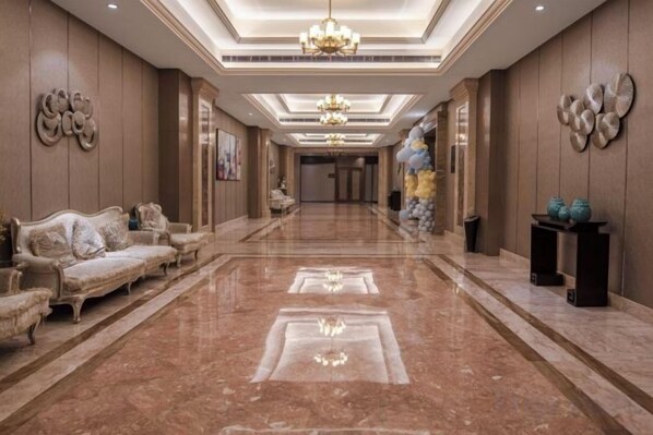 Un hall d’hôtel spacieux, doté d’un sol en marbre, d’un ensemble de canapés et d’un lustre.