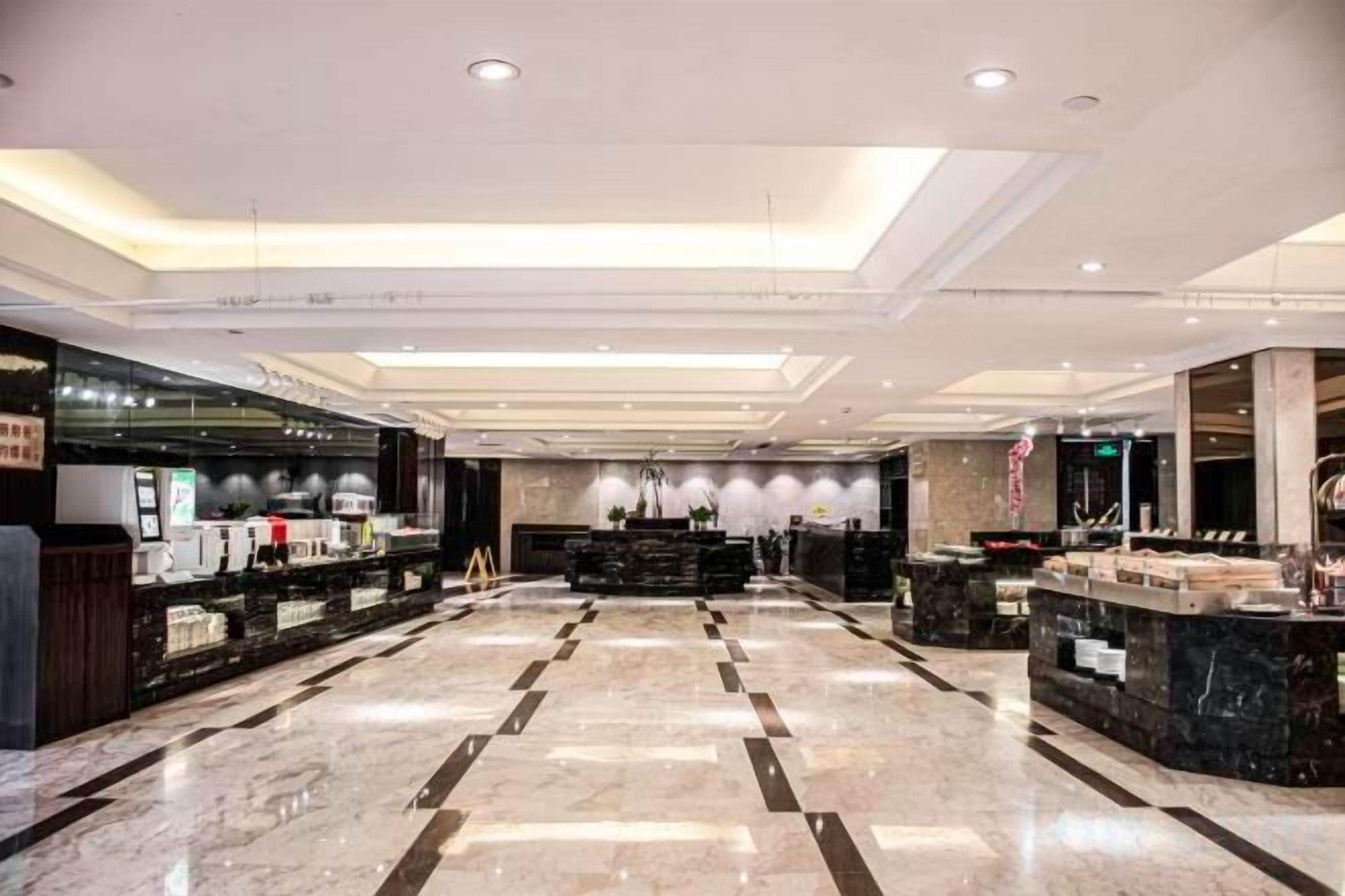 A spacious lobby with a marble floor, a reception desk, and a modern ceiling design.