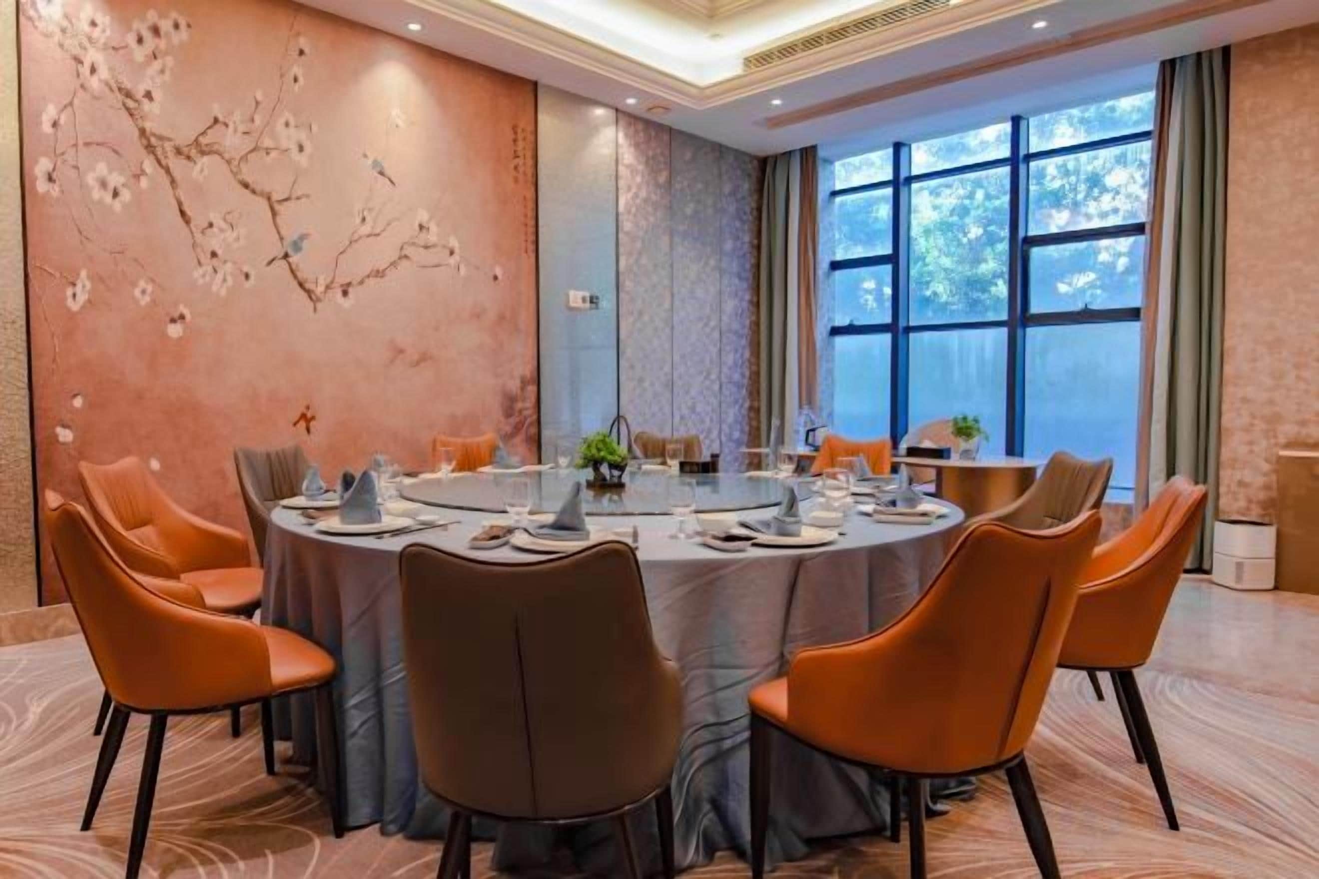 A conference room with a round table, chairs, and a decorative wall.