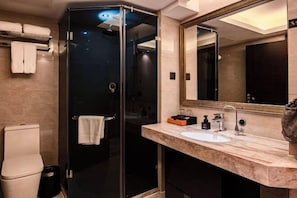 A modern bathroom with a glass-enclosed shower, a sink with a marble countertop, and a large mirror. - Shishi Wanjia International Hotel (Shishi)