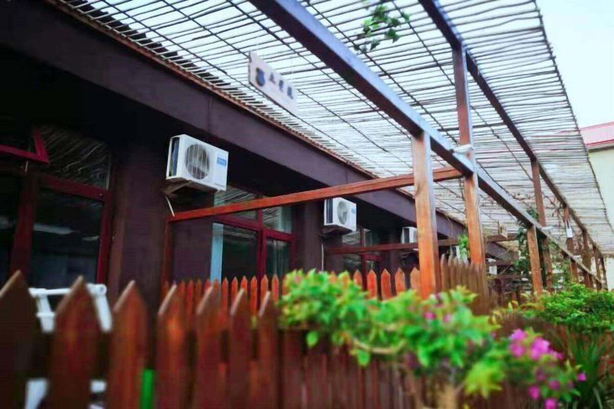 Ένα κτίριο με μεταλλική στέγη, μονάδες κλιματισμού και ξύλινο φράχτη.