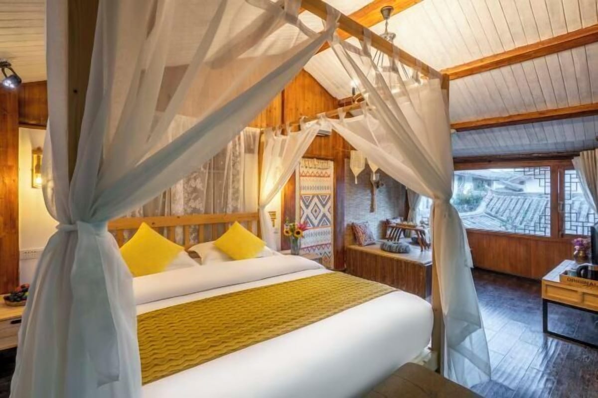 Una habitación con cama, un escritorio de madera y vistas al exterior.
