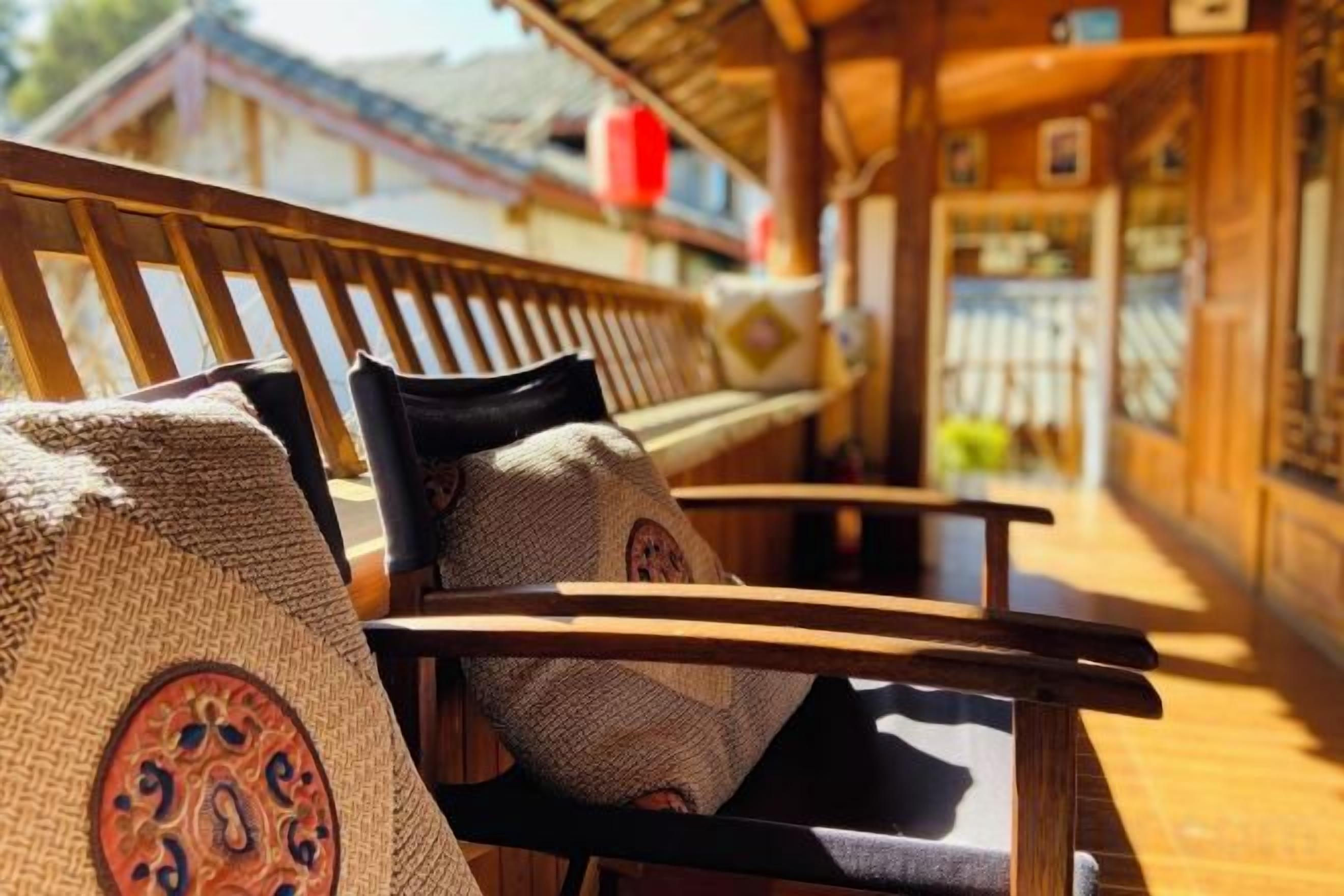 A wooden bench with woven cushions, a wooden railing, and a view of a building in the background.